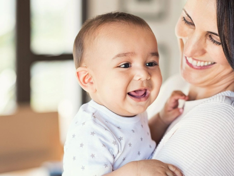 Mother Cuddling Happy Baby Boy At Home