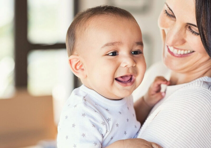 Mother Cuddling Happy Baby Boy At Home